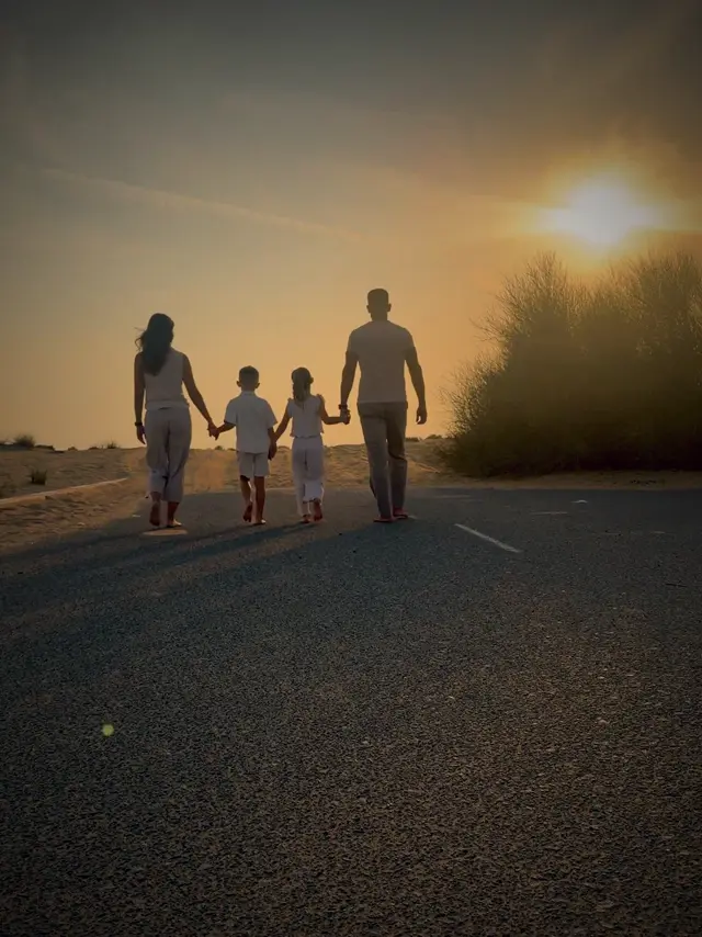 Angelina und Tassilo mit ihren Kindern bei Sonnenuntergang auf einer Wüstenstraße in Dubai